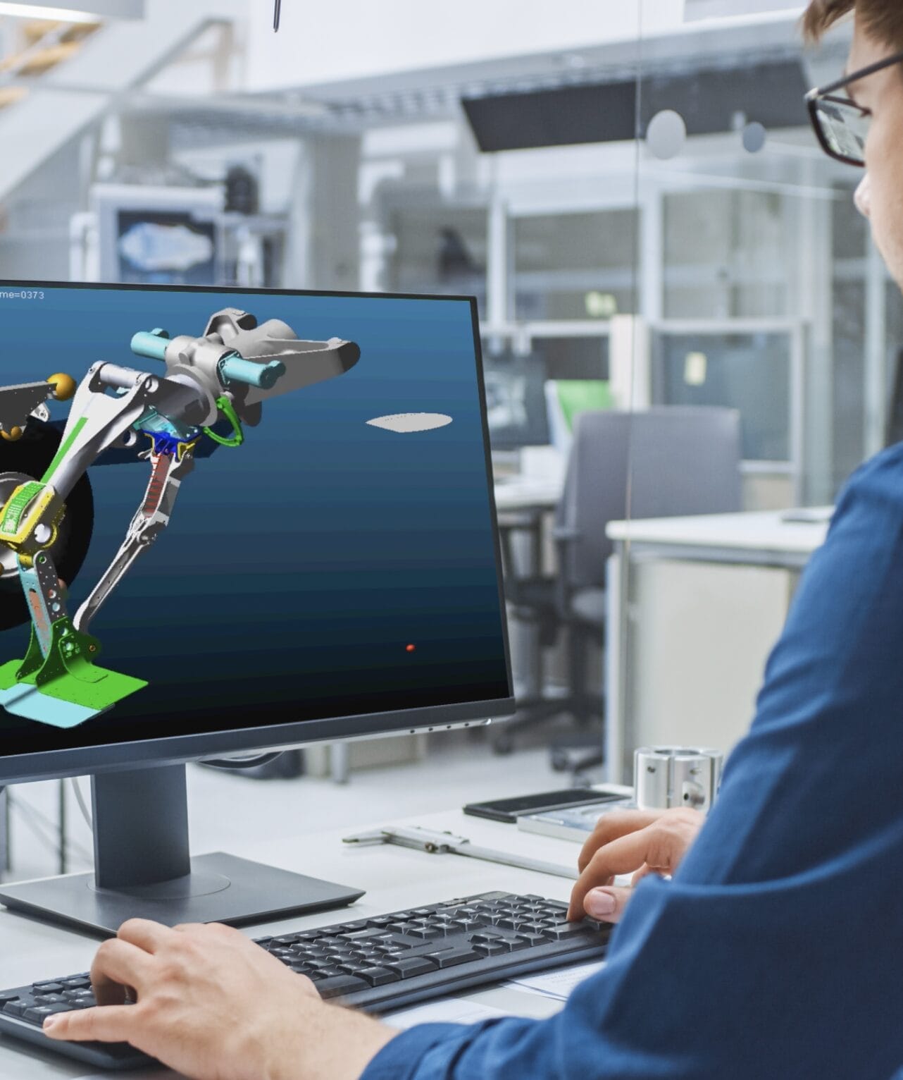 Photograph of an engineer behind a monitor displaying an aircraft part